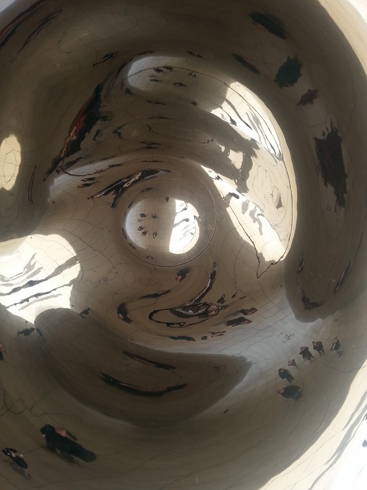 A distorted reflection of the people under the Cloud Gate sculpture.